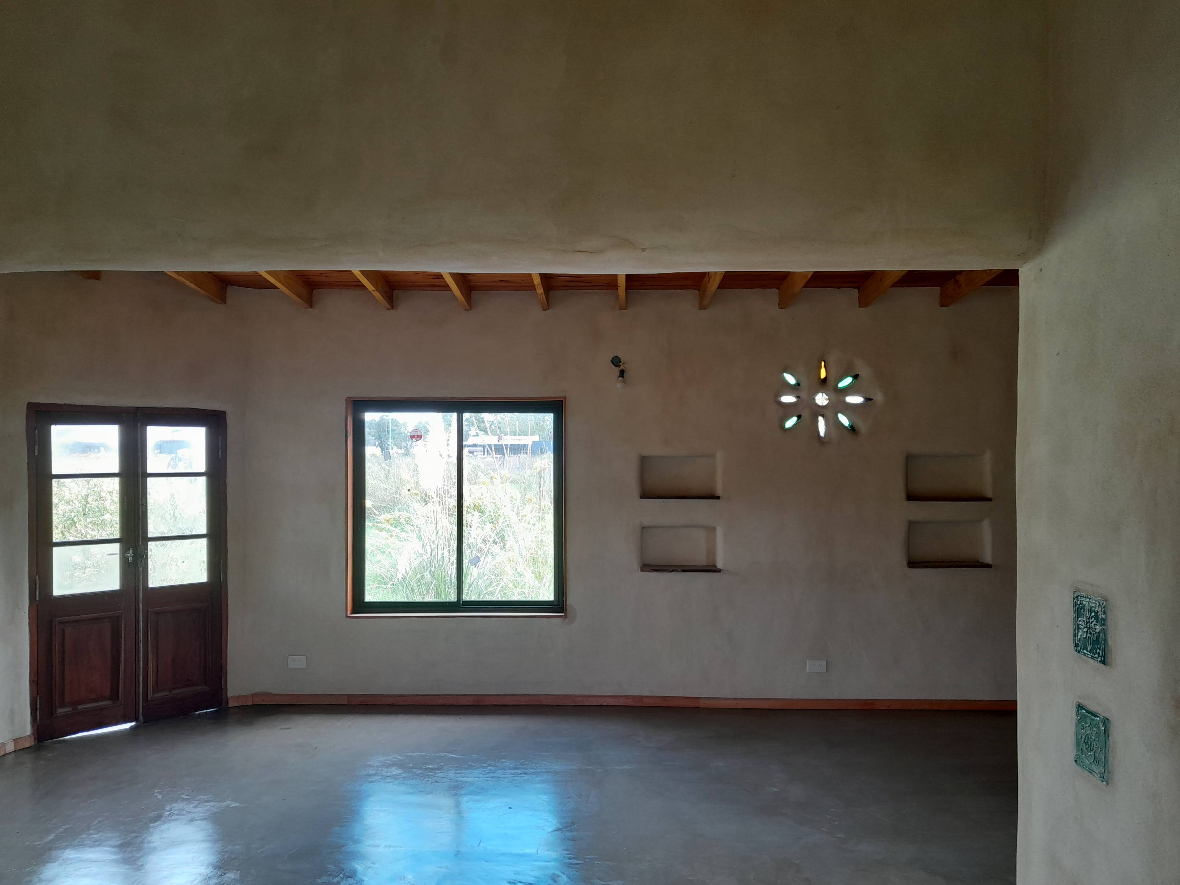 La habitación sin amueblar, única, sin alfombra, con grandes ventana altas y con dos puertas claras, paredes De colores cl...