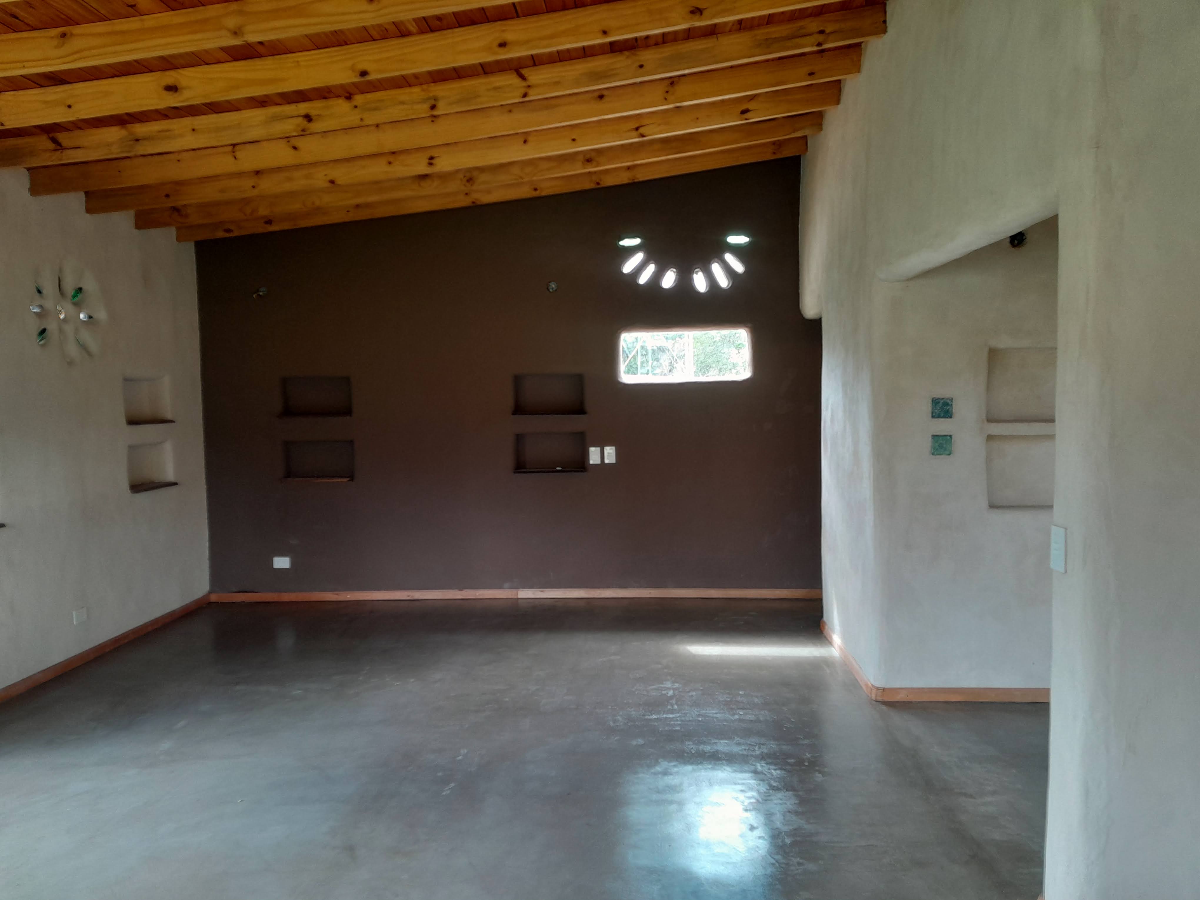 The interior of an unfurnished space, featuring a striking vaulted wooden ceiling, dark brown walls, a narrow rectangular ...