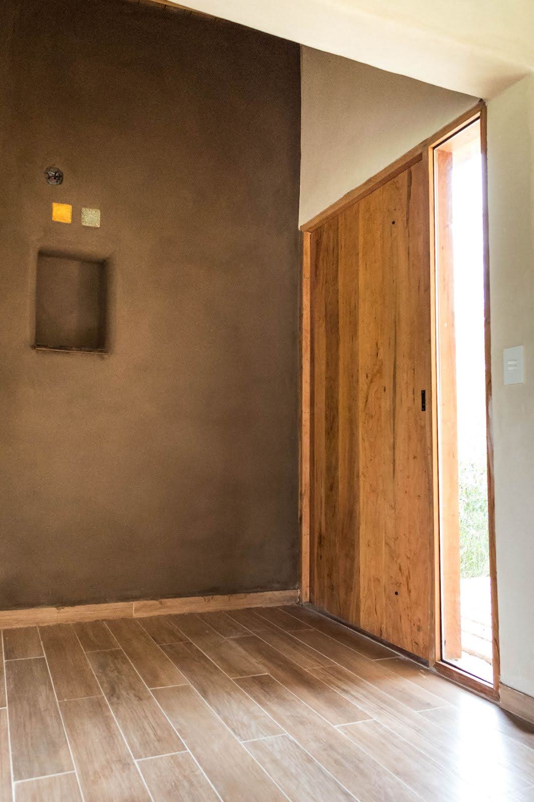 bare interior room with brown wall, wooden floor, door and opening on its top.